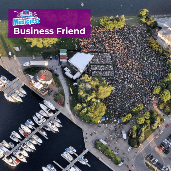 overhead photo of a concert with a lot of attendees. The venue is by a lake full of boats.