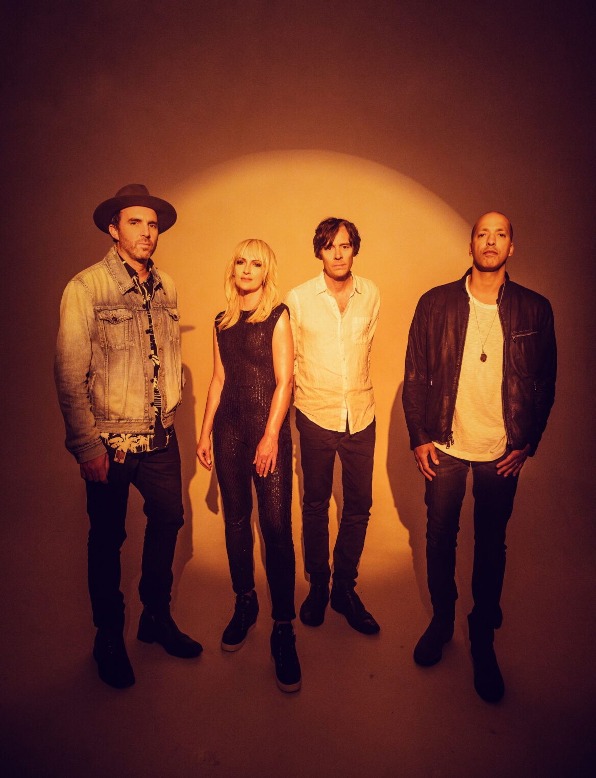 A band portrait group photo with a warm camera filter effect and with all four band members standing casually looking into the camera